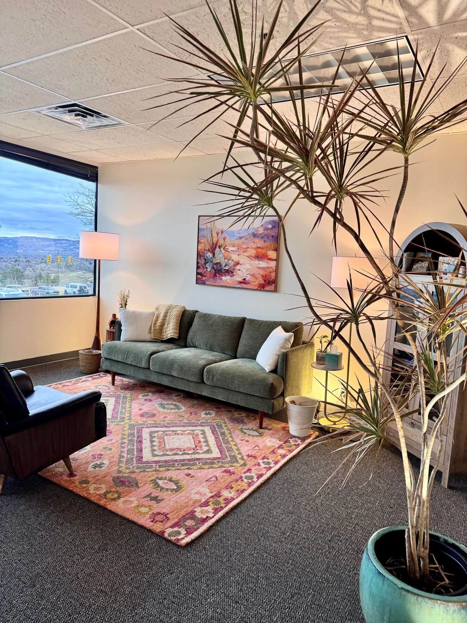 A private therapy office with a sofa, chairs, plants, and windows over Salt Lake City